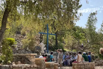 Pilgrims beside the Blue Cross and Our Lady’s statue at an Apparition Hill tour stop in Medjugorje